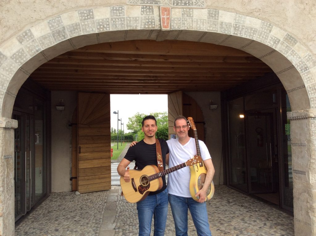 Zwei Männer mit gitarre vor einem großen Haustor