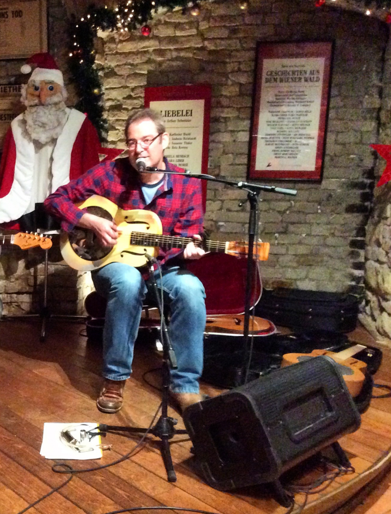 Mann in weihnachtlicher Kulisse singt und spielt Gitarre